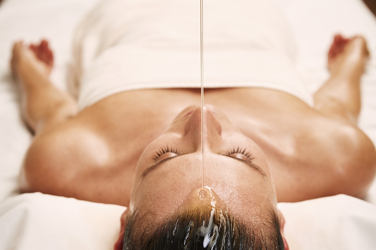 Frau wird Öl auf den Kopf gegossen bei Massage