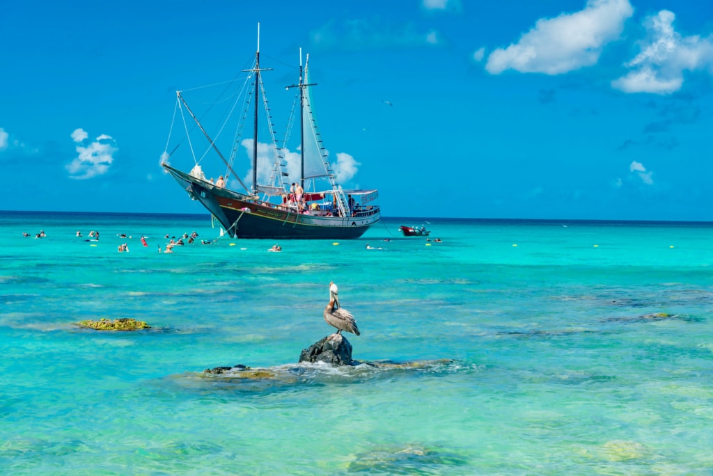 Türkisfarbenes Meer auf Aruba, Segelschiff im Hintergrund