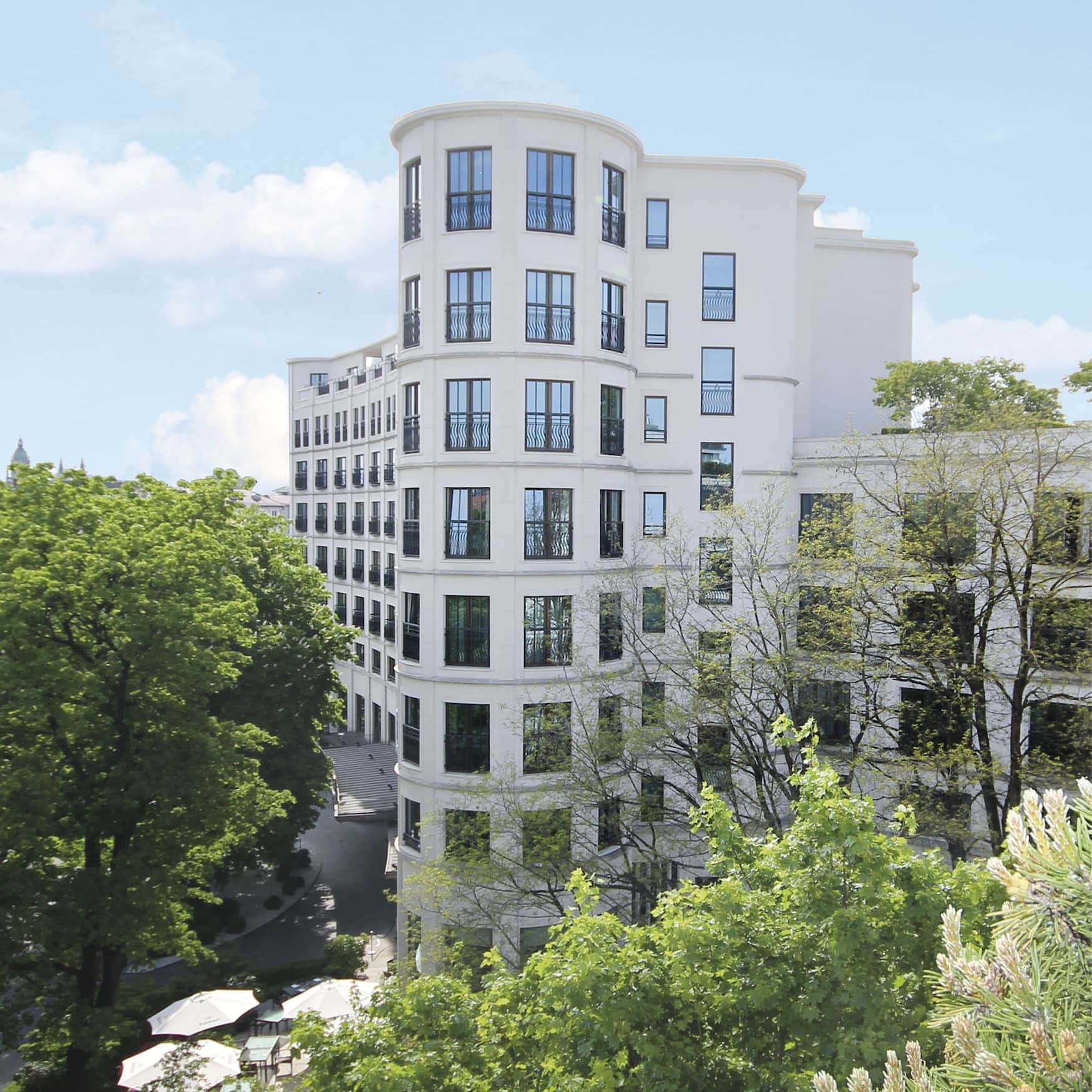 Außenfassade eines Grandhotels in München umgeben von grünen Bäumen