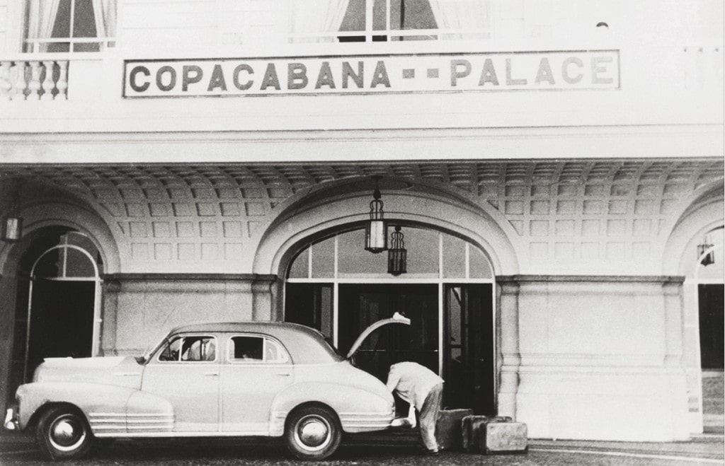 Schwarz-weißes Archivbild: Mann lädt vor Eingang des Copacabana Koffer aus Auto