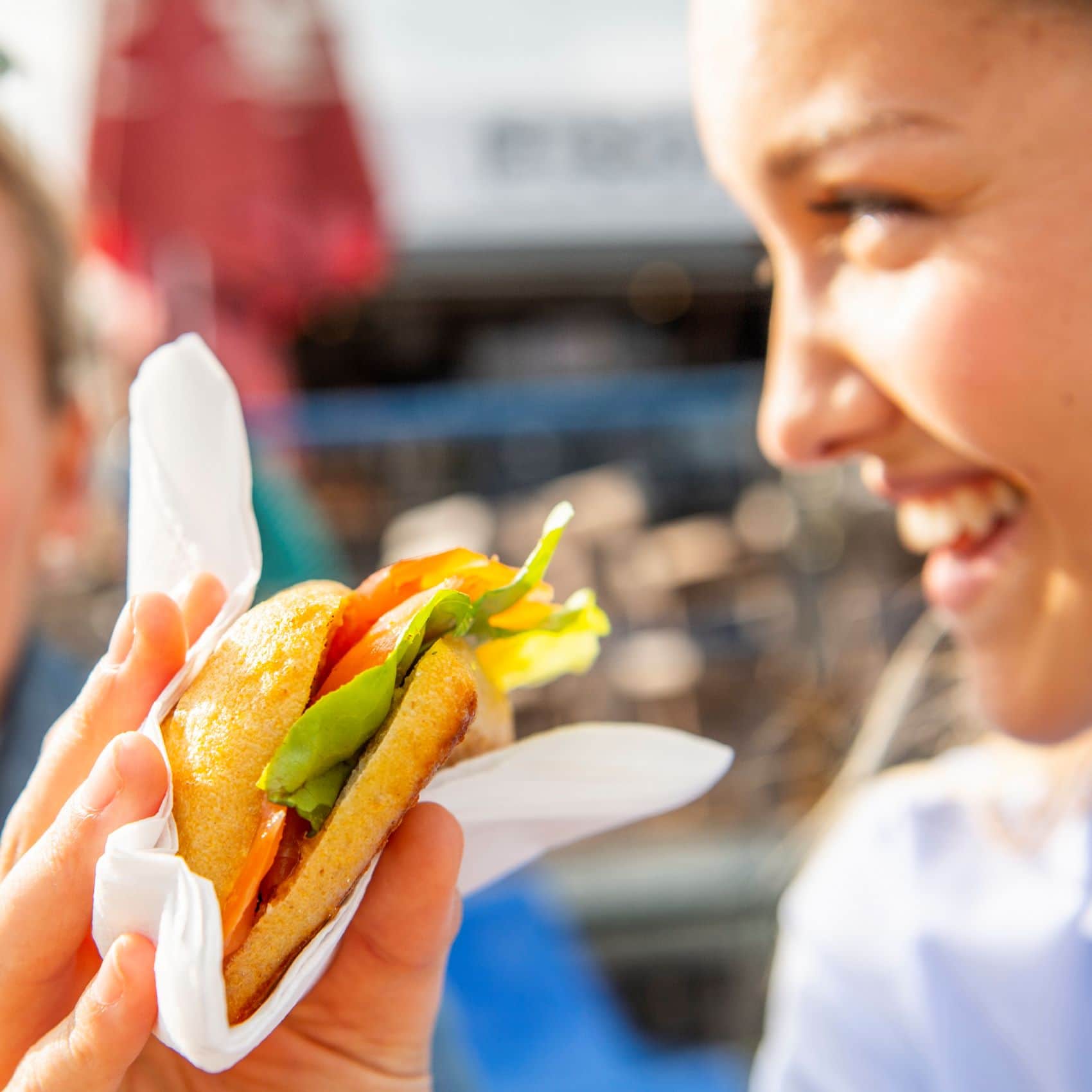 Lächelnde Frau hält Fischbrötchen in der Hand 