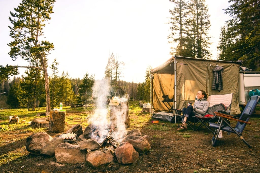 Frau sitzt auf Stuhl neben ihrem Campingzelt