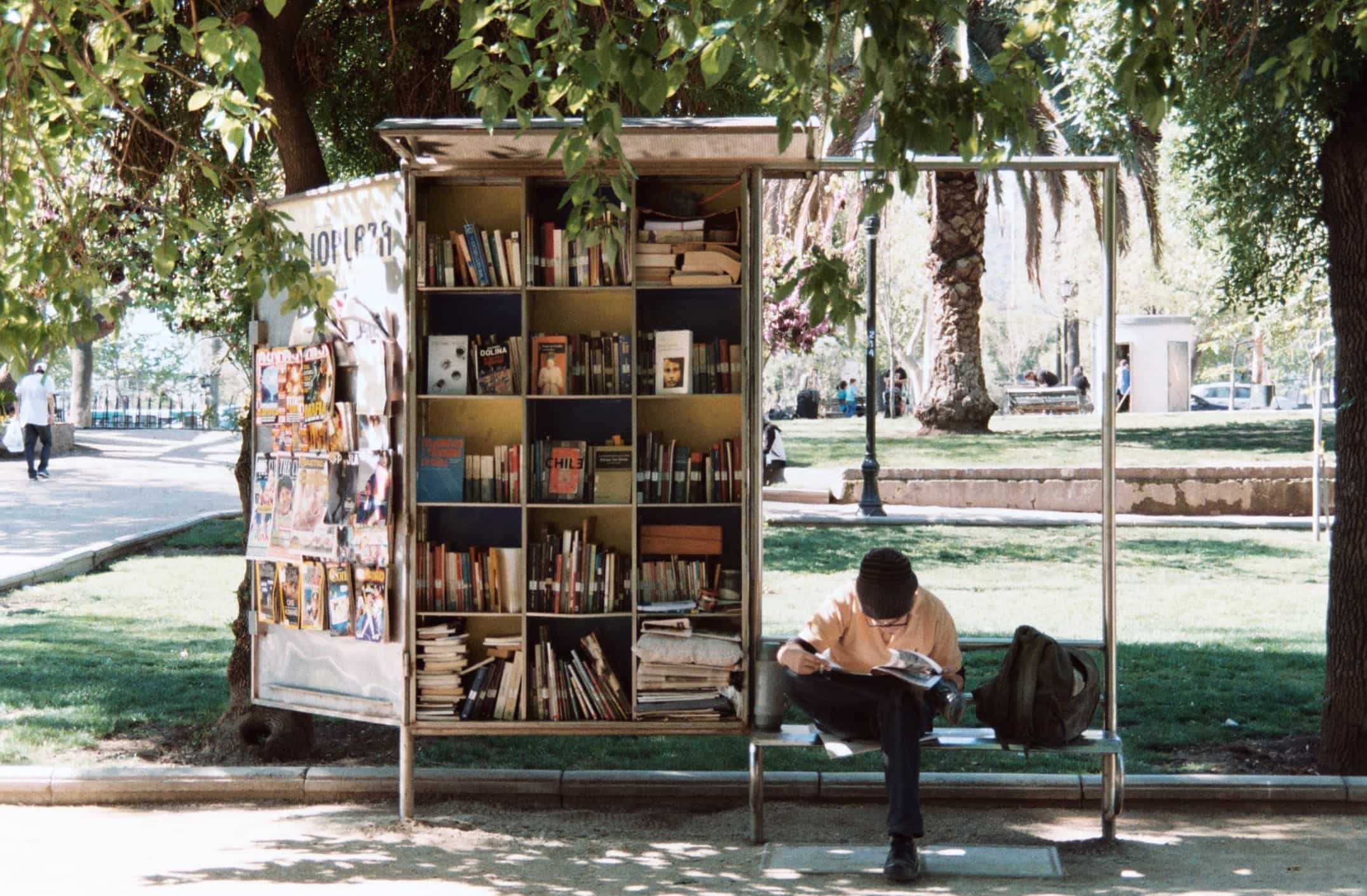 Junger Mann sitzt auf einer Bank in Santiago de Chile und liest ein Buch
