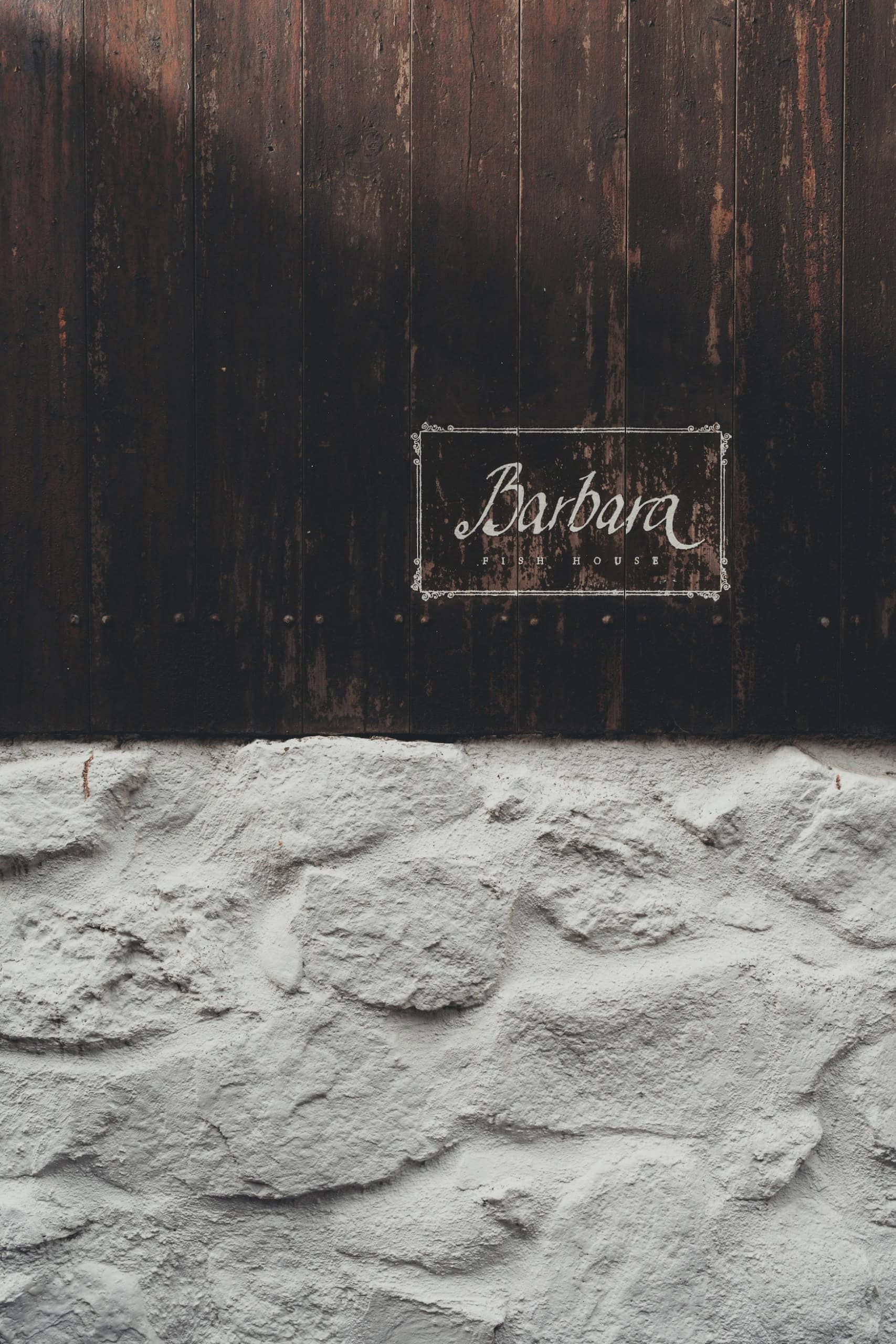 Schild des Barbara Fish House an einer Holz- und Steinmauer in Tórshavn, Färöer-Inseln.