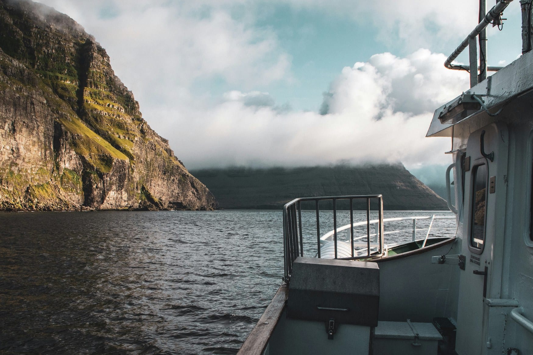 Blick vom Deck einer Fähre auf den Fjord zwischen den Klippen der Färöer-Inseln