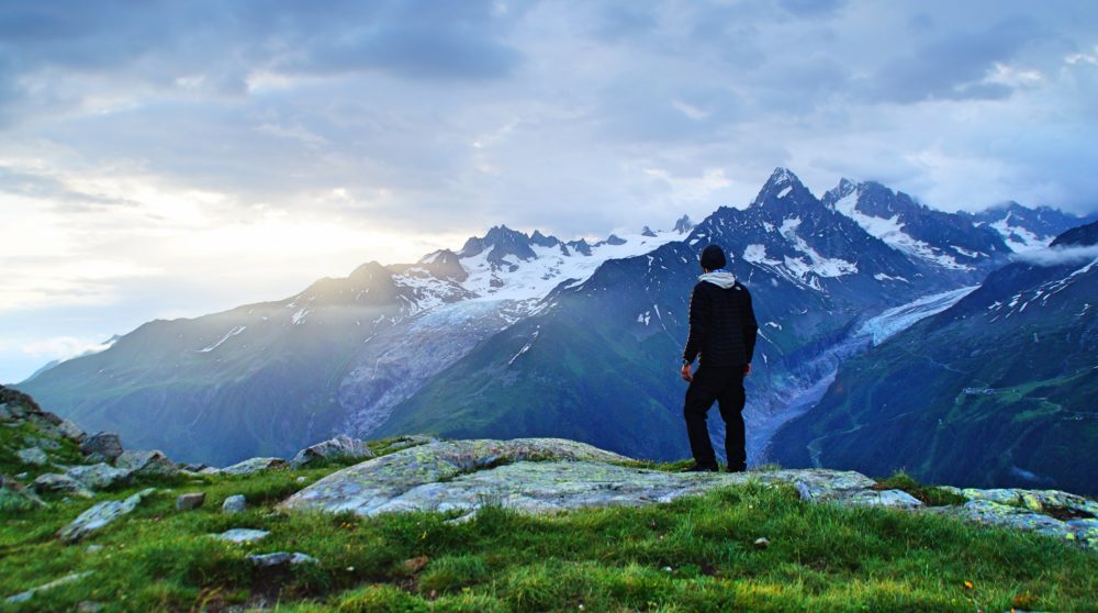Alpenpanorama und junger Mann bei Dämmerung
