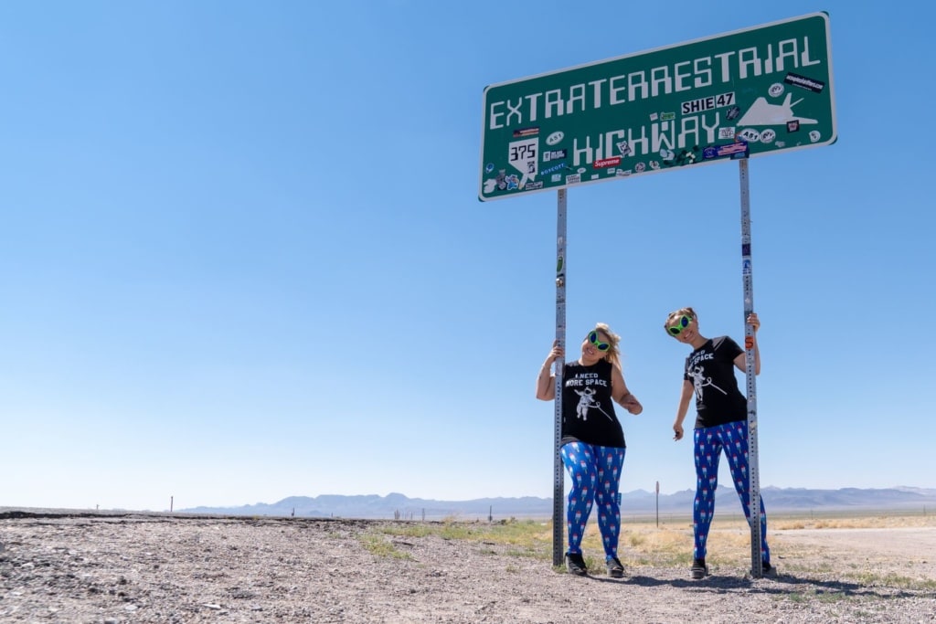 Zwei Frauen posieren vor einem Schild auf der Route 375 in Nevada