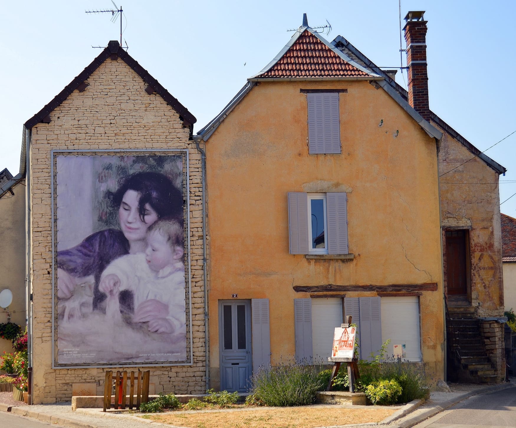 Bild von einer Straße in Essoyes in Frankreich, wo große Reproduktionen des berühmten Malers Renoir das Straßenbild schmücken.