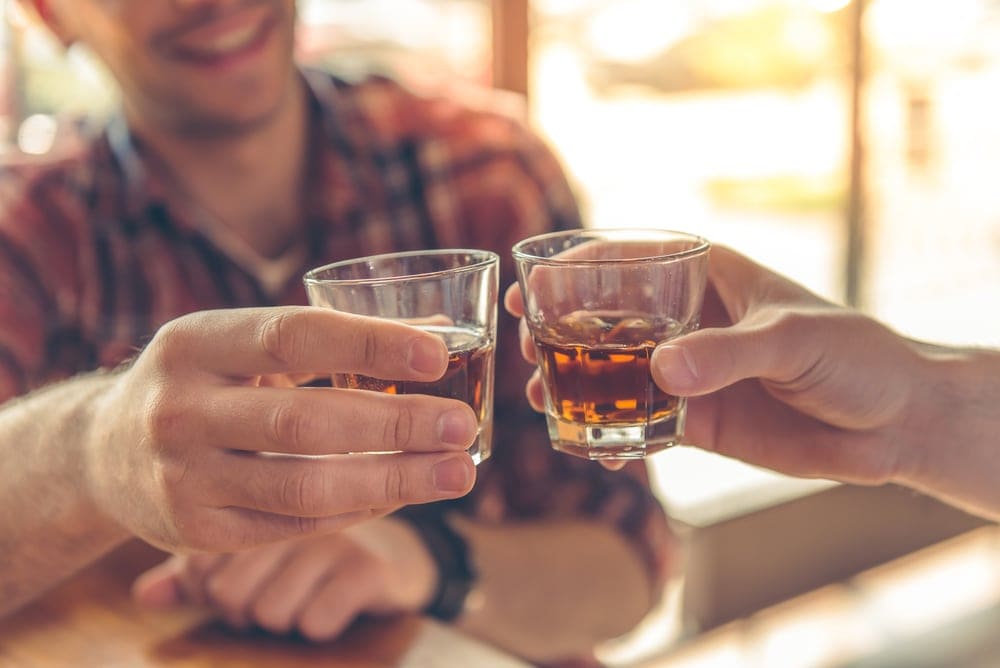 Mann stößt mit Whiskey-Glas an