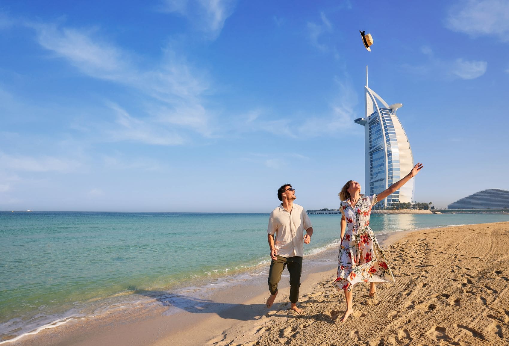 Junges Paar geht fröhlich entlang des Jumeirah Beach in Dubai
