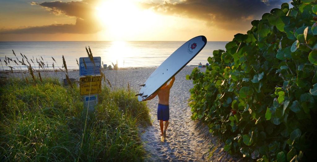 Mann geht mit Surfboard zum Lake Worth Beach in Florida