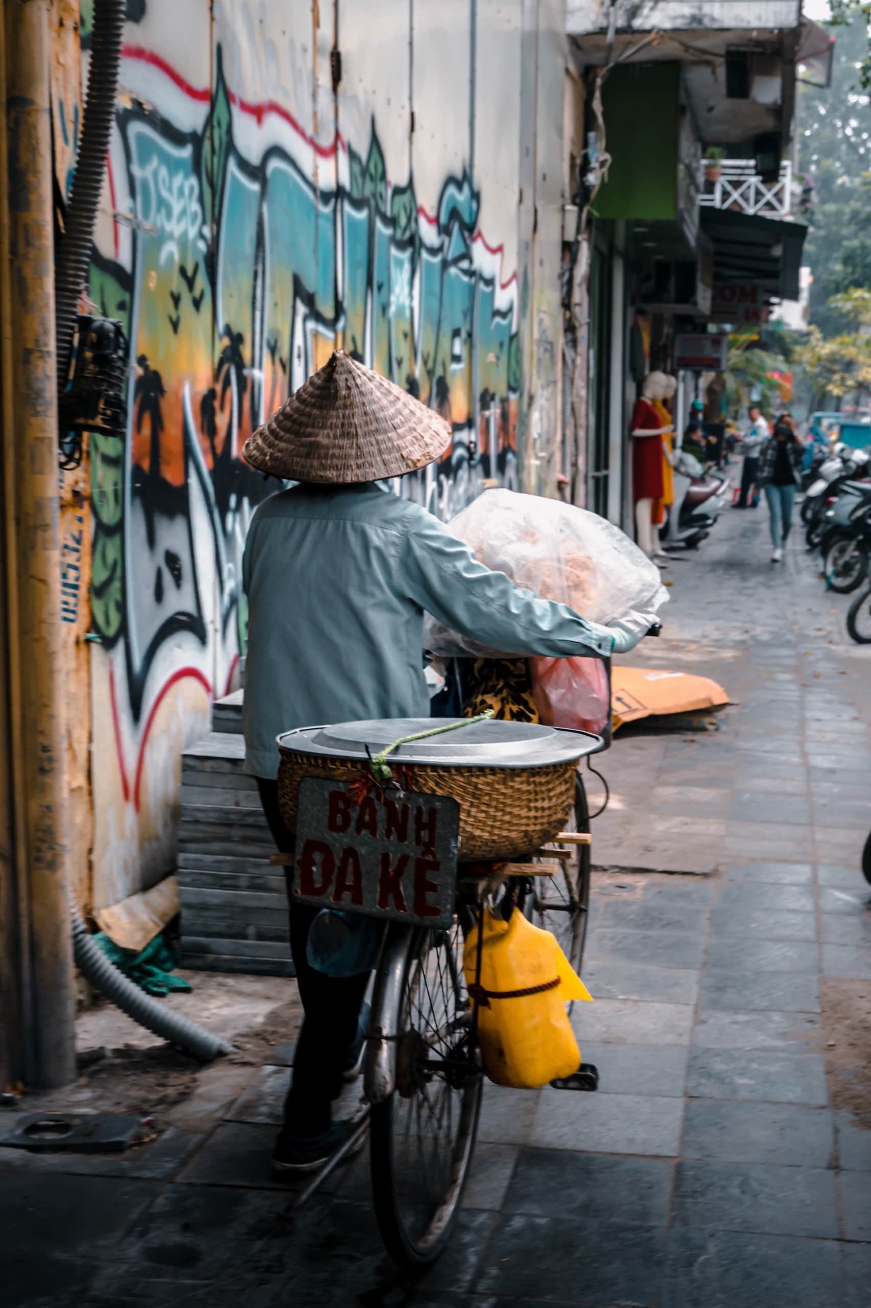 Einheimischer in Hanoi, Vietnam, fährt mit Fahrrad und trägt einen typischen Reishut