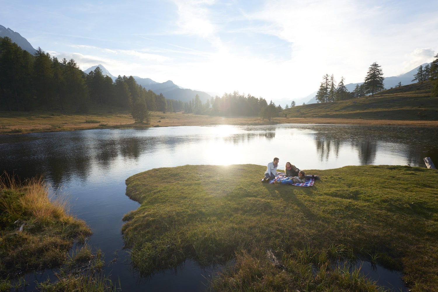 Familie liegt auf Picknickdecke vor dem Lai Nair in Graubünden