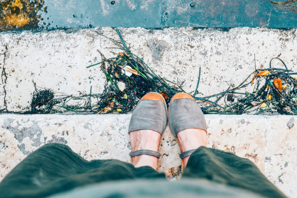 Frau mit Espadrilles steht auf Stufe am Hafen