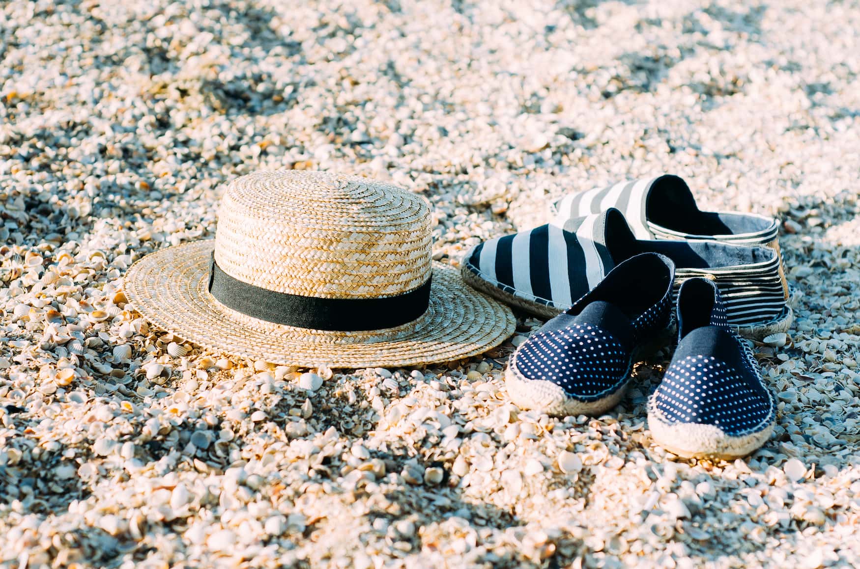 Espadrilles und Strohhut liegen auf Sand an Strand in Frankreich