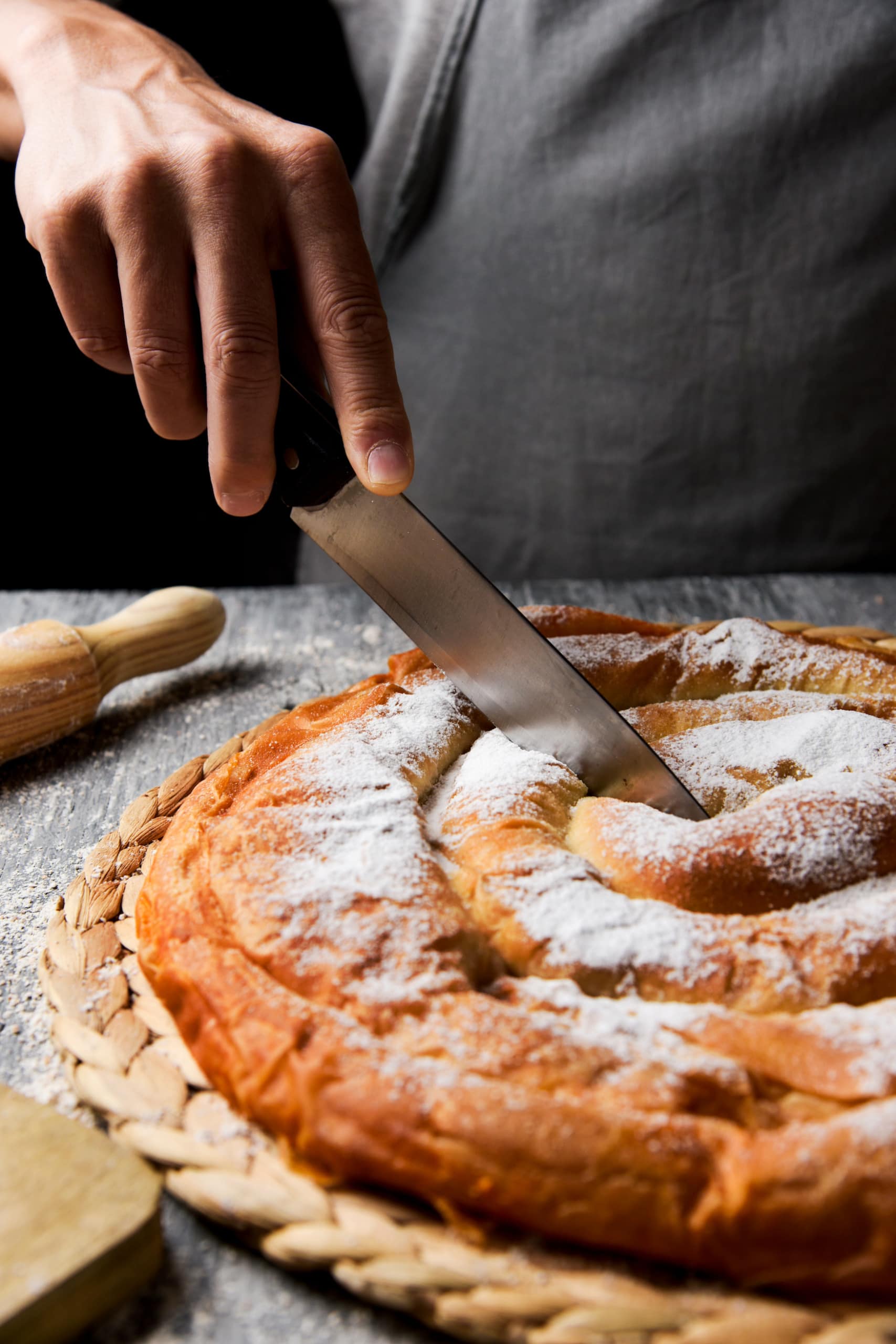 Mallorquinische Tarte wird von Mann angeschnitten
