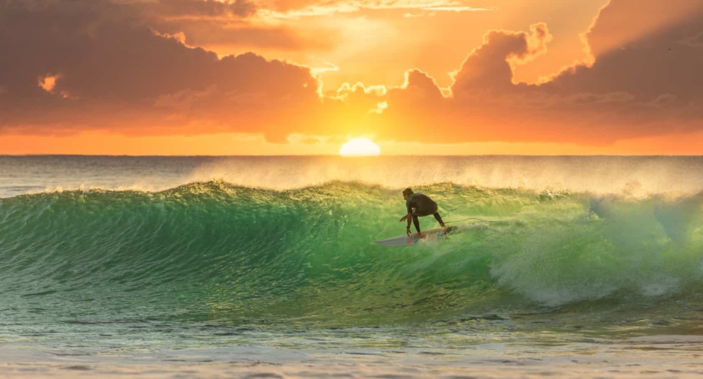 Surfer reitet die perfekte Welle im Sonnenuntergang.