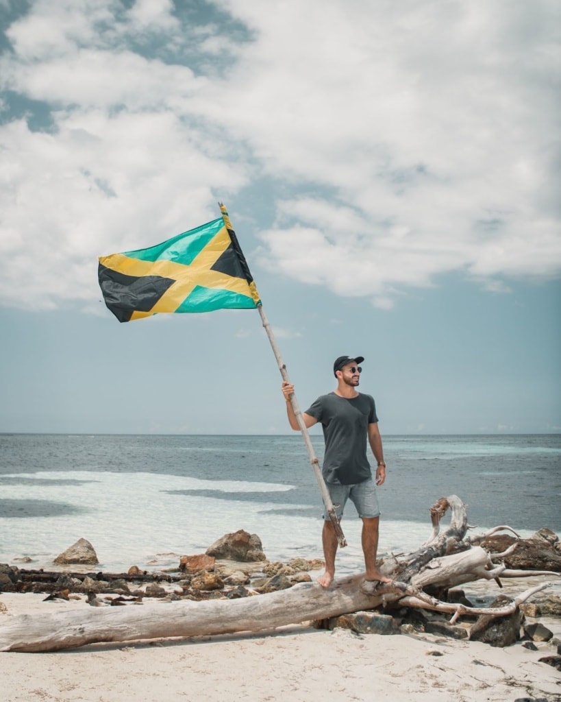 Mann am Strand mit Flagge Jamaikas