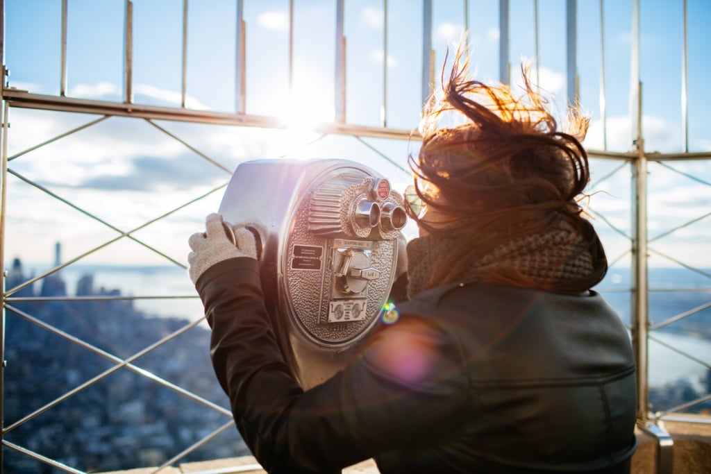 Frau auf dem Empire State Building versucht die Aussicht trotz Wind zu genießen