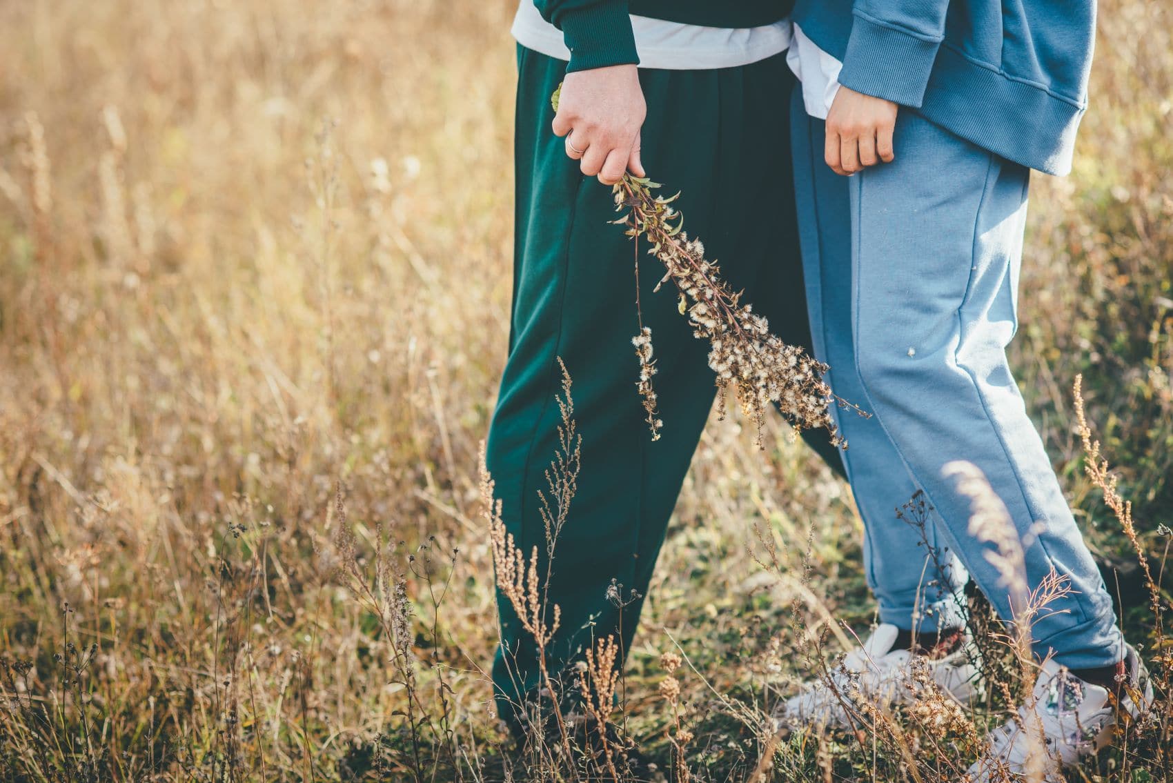 Paar in Jogginhosen steht auf Wiese zusammen