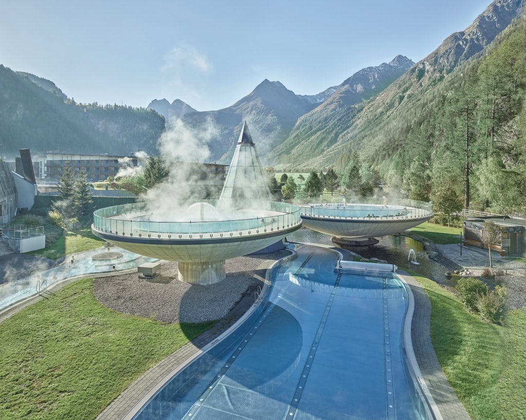 Blick auf die Außenbecken des Hotel AUQA DOME - Tirol Therme Längenfeld mit Bergpanorama
