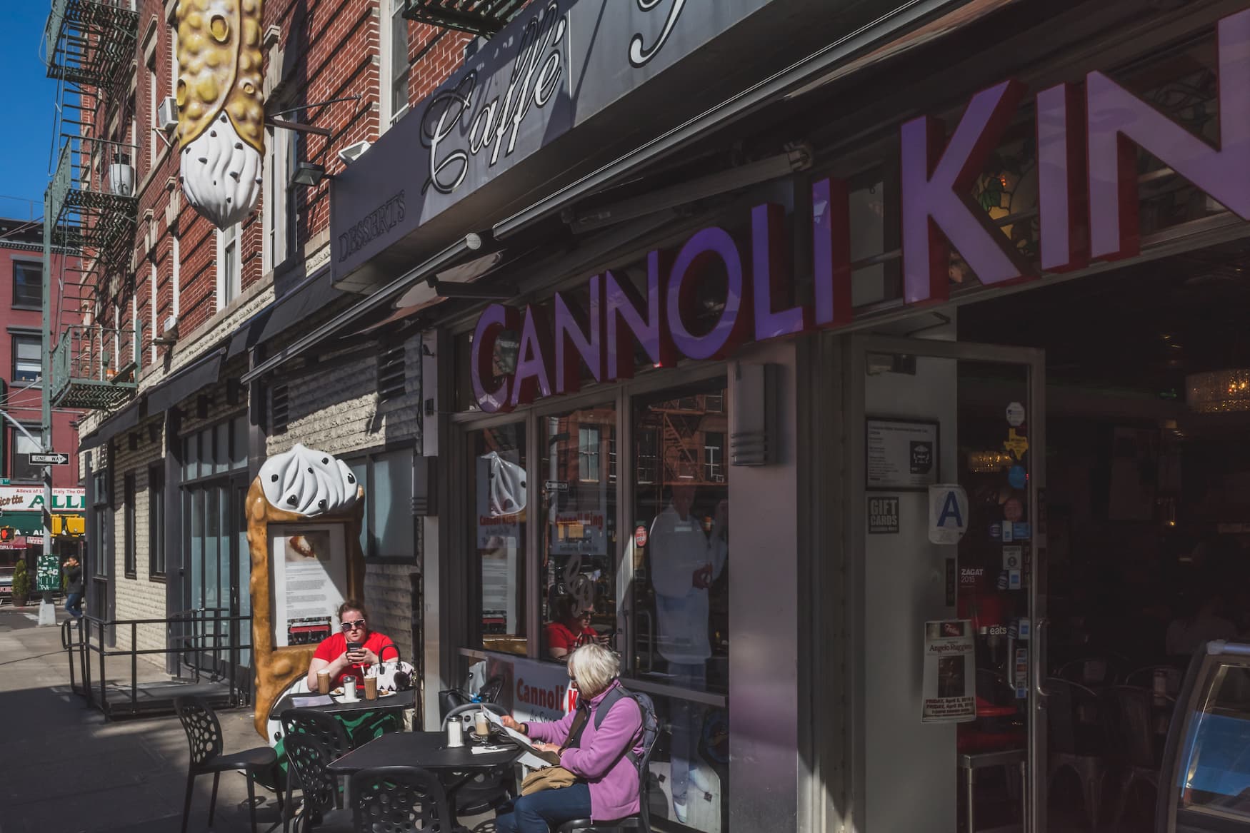 Leute sitzen vor einem bekannten Restaurant in Little Italy in New York City, dem Caffé Palermo, bekannt für seine ausgezeichneten Cannoli