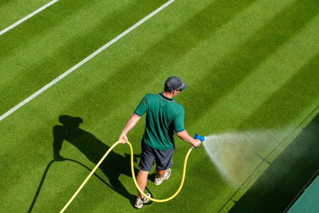 Wimbledon-Arbeiter mit Wasserschlauch auf Tennisplatz