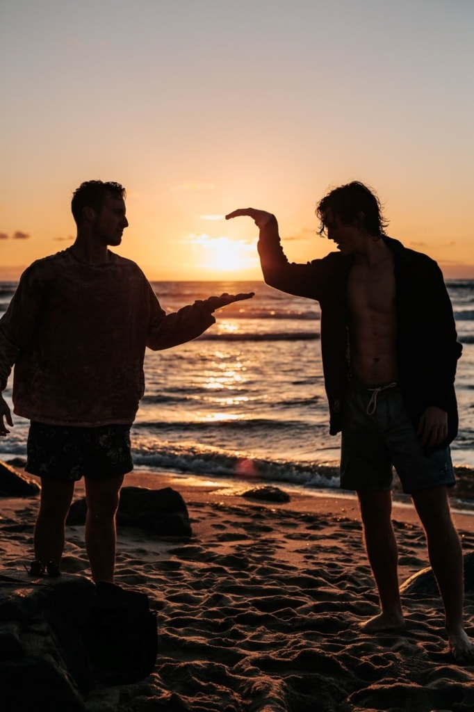 Zwei junge Männer schlagen sich am Strand in die Hand