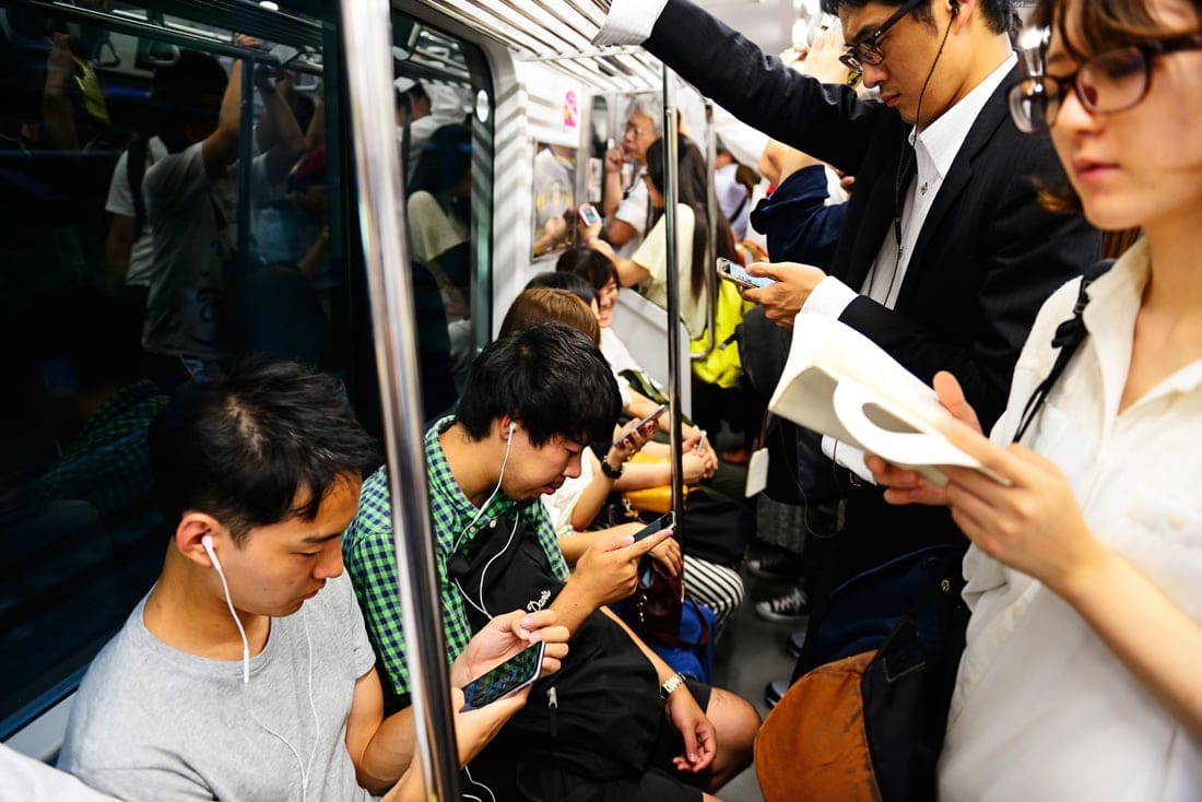 U-Bahn-Fahrer nutzen Smartphones in Tokio, Japan