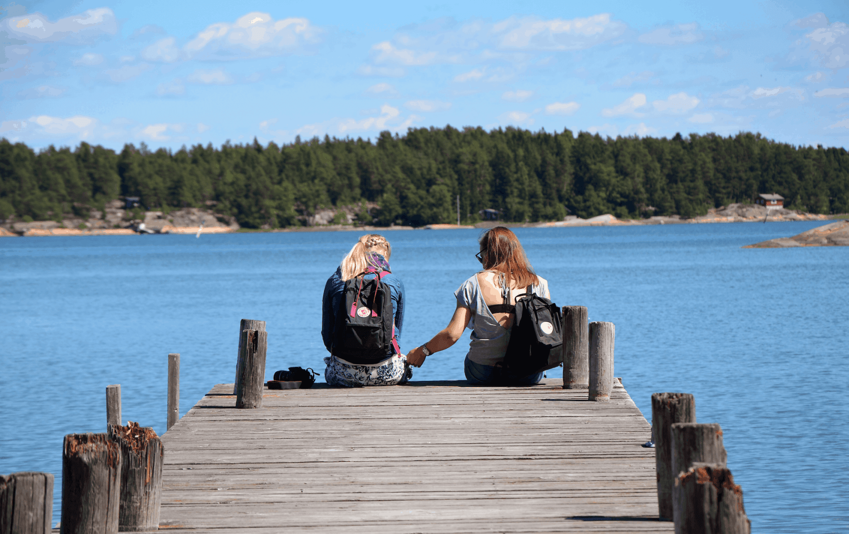 Finnland: Zwei jungen Frauen sitzen auf einem Steg