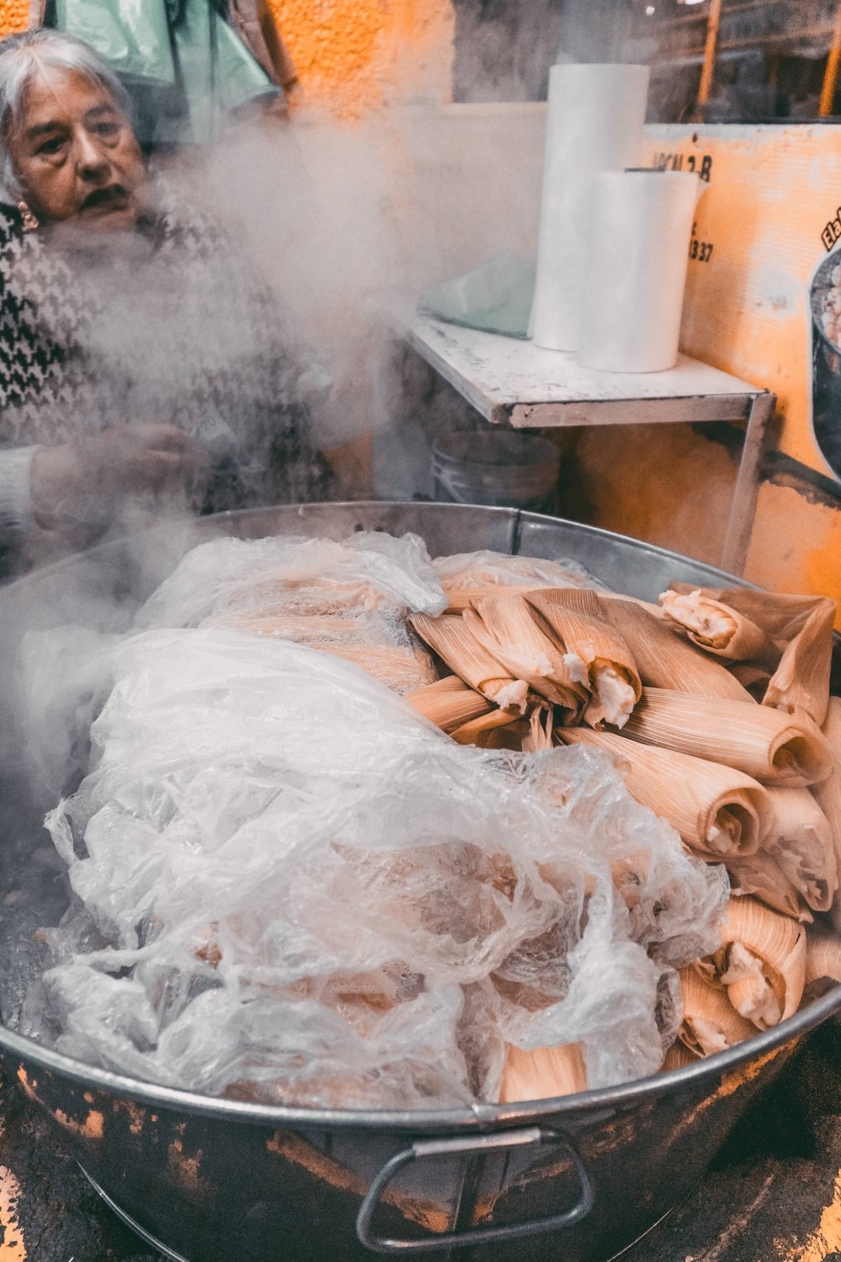 Tamales garen in riesigen Kochtopf vor sich her. Qualm steigt auf