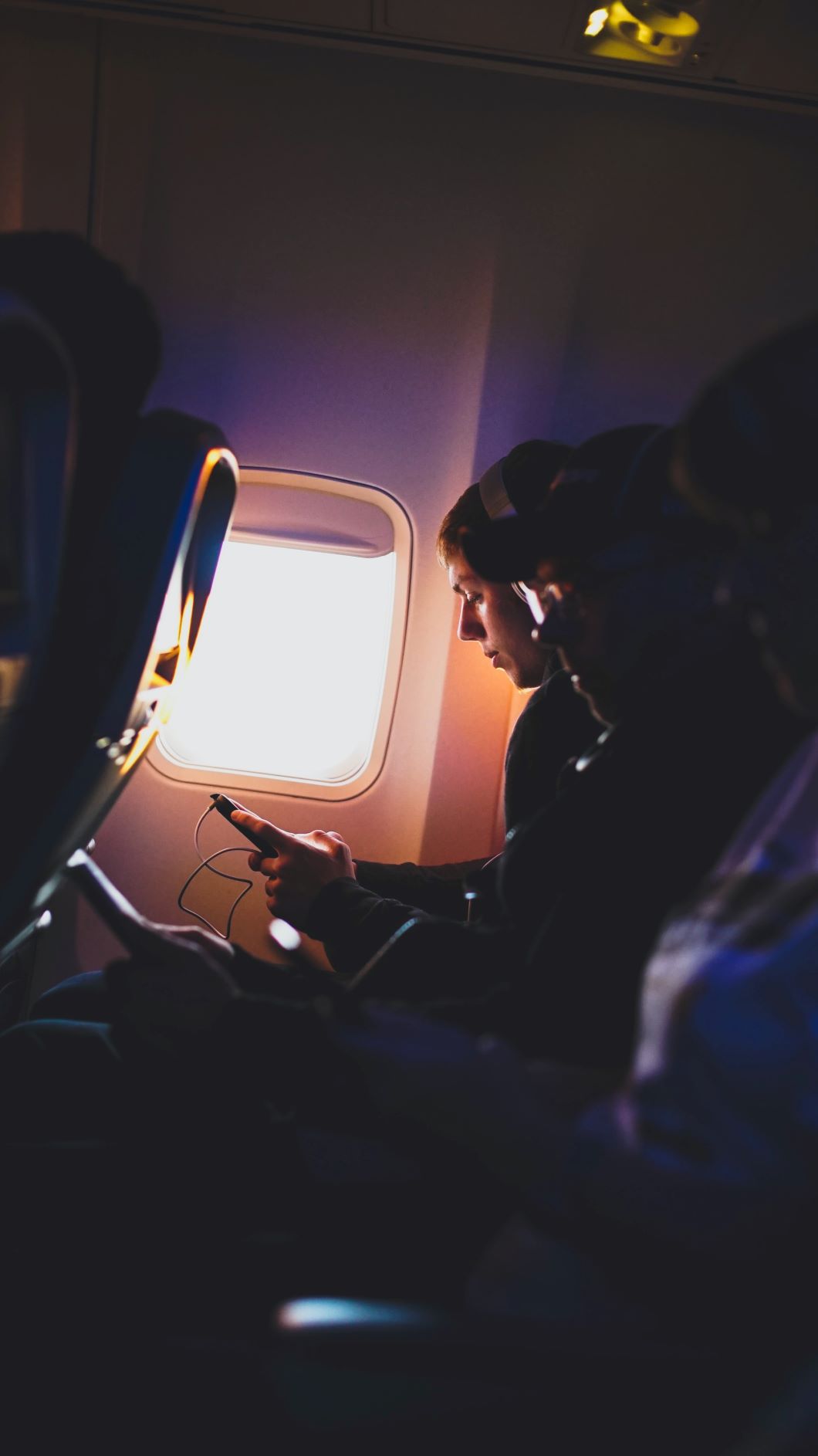 Drei Passagiere sitzen im Flugzeug in einer Reihe 