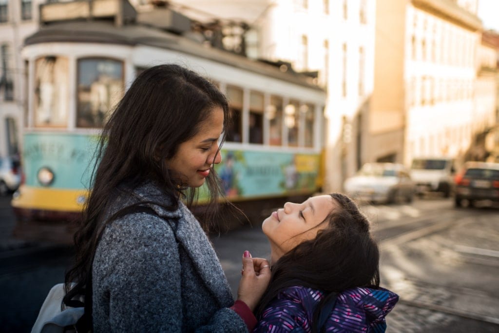 Mutter und Tochter lächeln sich an in Straße in Lissabon, Portugal