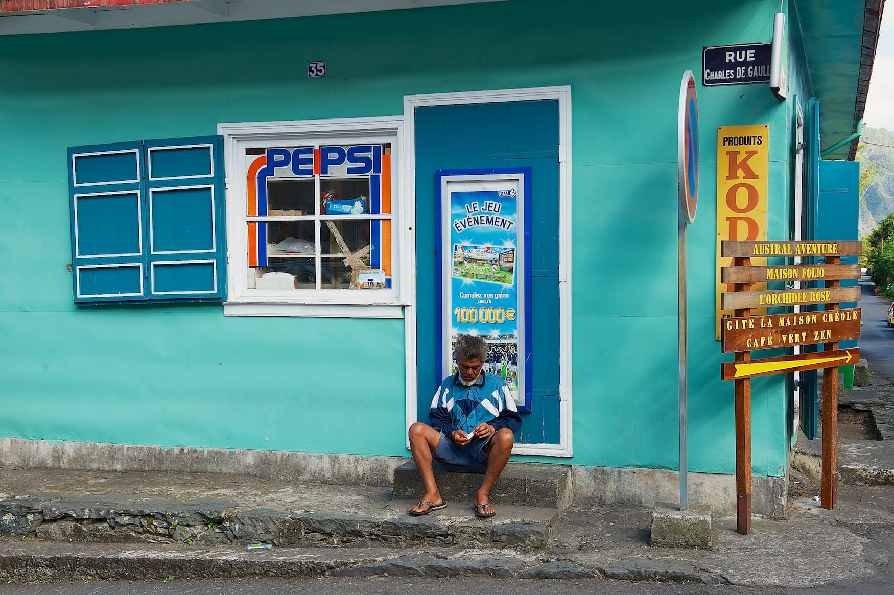 Mann sitzt vor buntem Haus in La Reunion