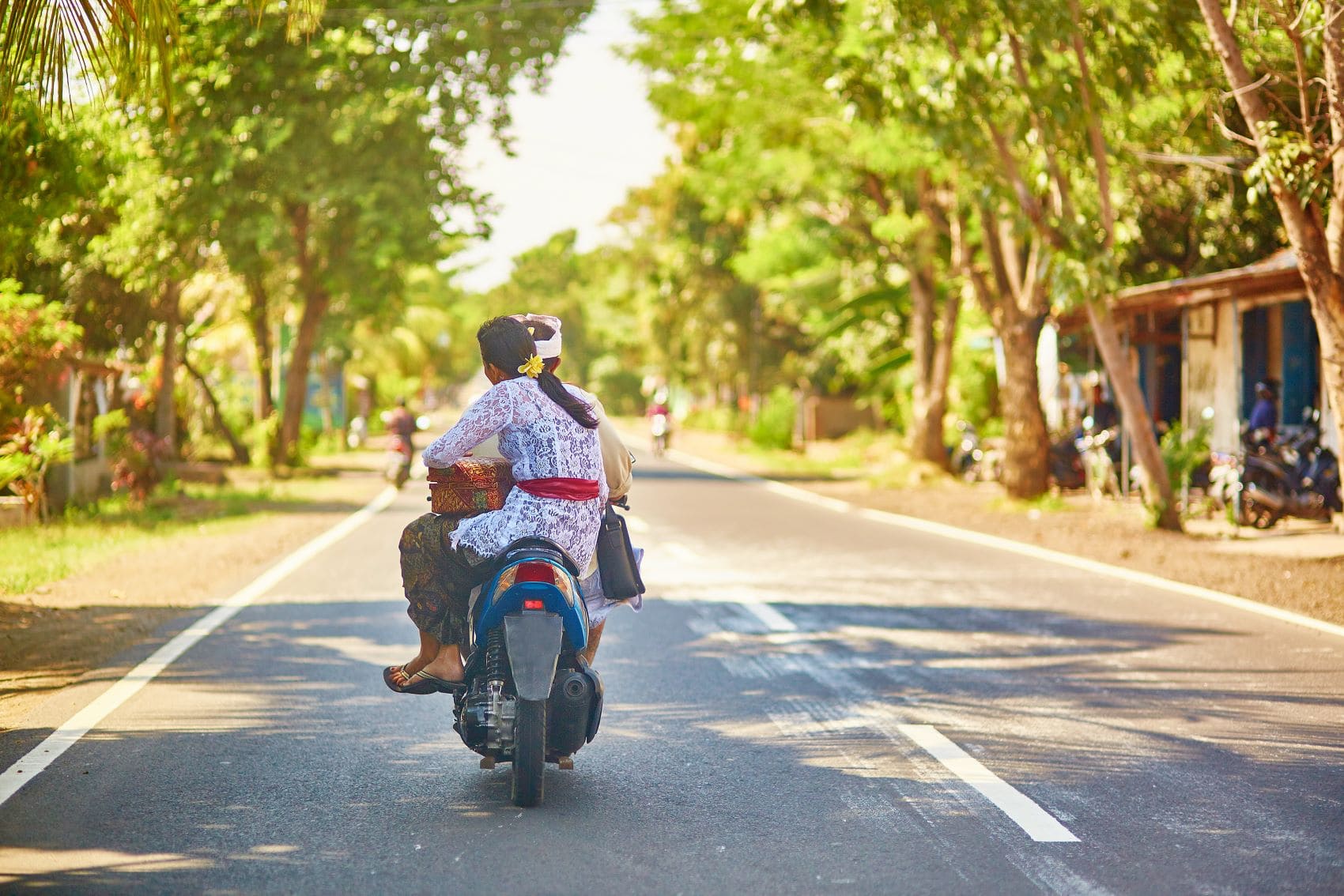 Moped mit Mann und Frau fährt über Straße in Bali 