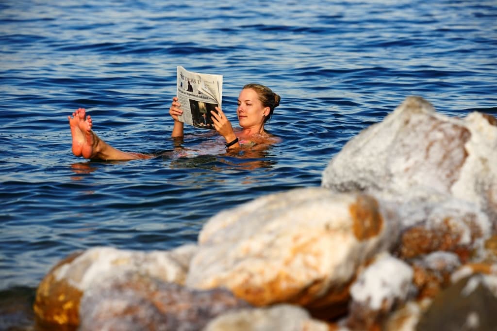 Frau liegt im Toten Meer und liest Zeitung