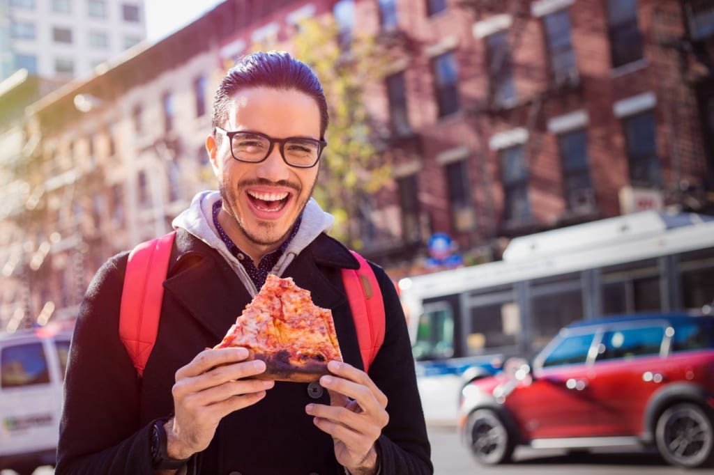 Mann isst Pizza auf Straße