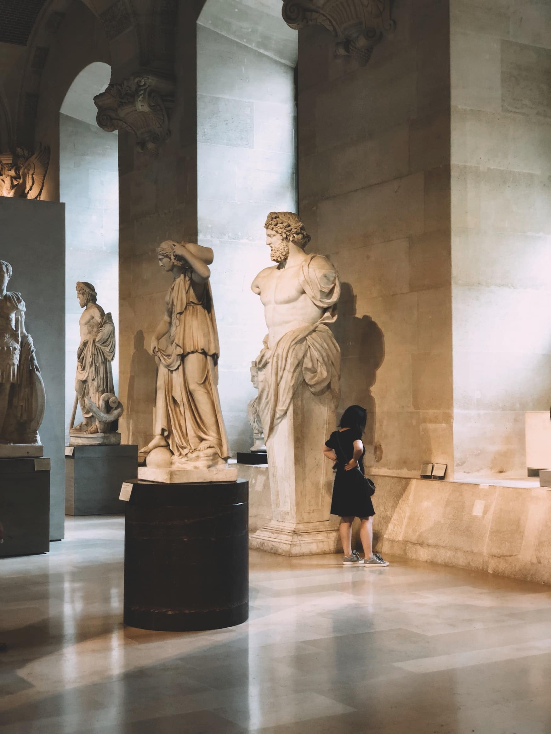 Besucherin guckt sich Statuen im Louvre in Paris an