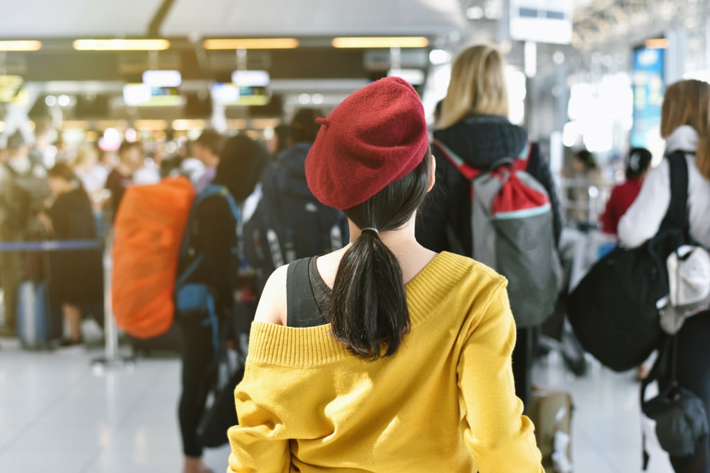 Mädchen mit roter Mütze steht in der Schlange vor dem Check-In-Schalter