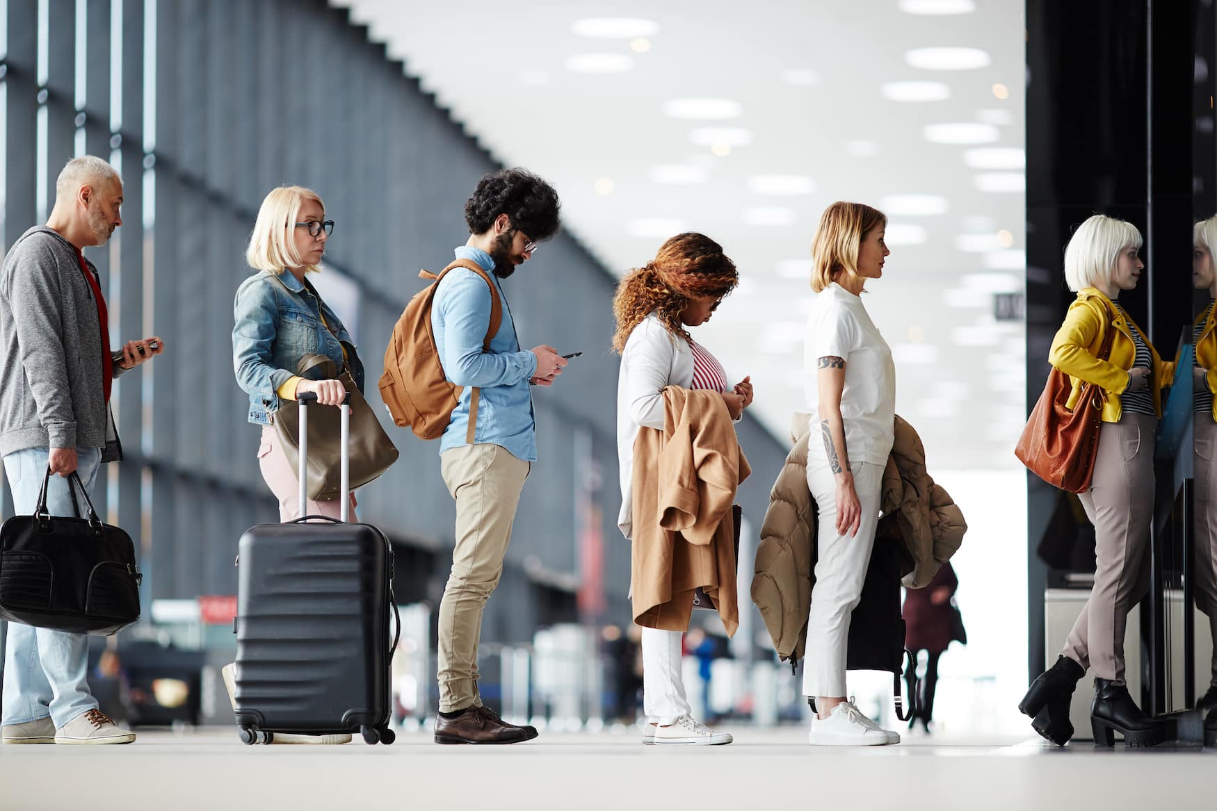 Reisende stehen in Warteschlange am Check in Schalter am Flughafen