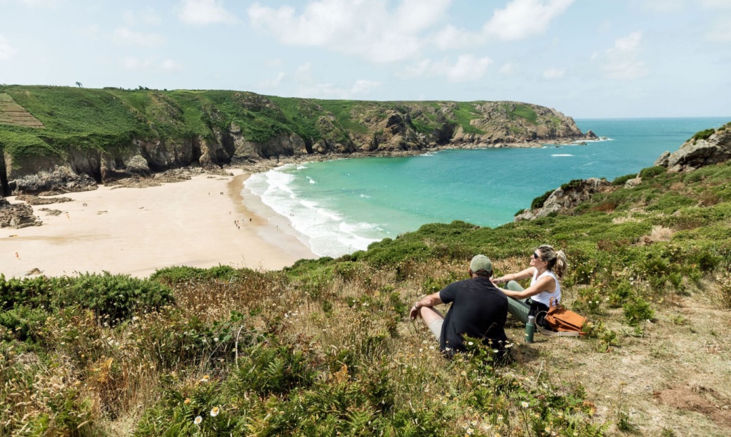 Mann und Frau sitzen auf einem Hügel in der Plemont Bay auf der Insel Jersey