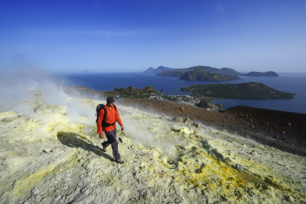 Wanderer auf dem Gran Cratere läuft durch Schwefelfumarolen, Blick auf Lipari, Salinas, Stromboli. Insel Vulcano, Liparische oder Äolische Inseln, Sizilien, Italien, Europa