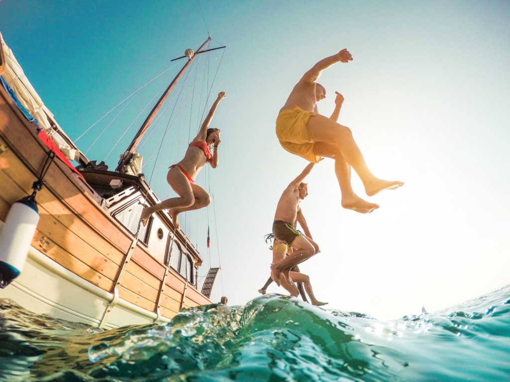 Gäste eines Segelschiffs springen ins Meer
