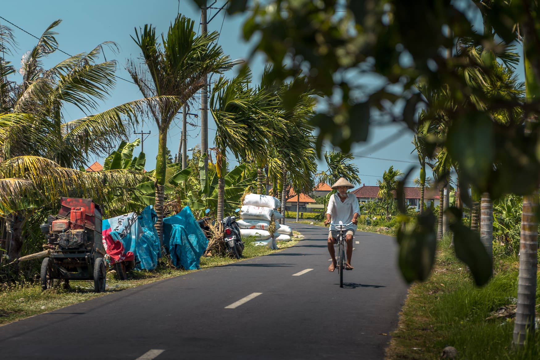 Asiatischer Mann fährt Fahrrad über ruhige Straße auf Bali
