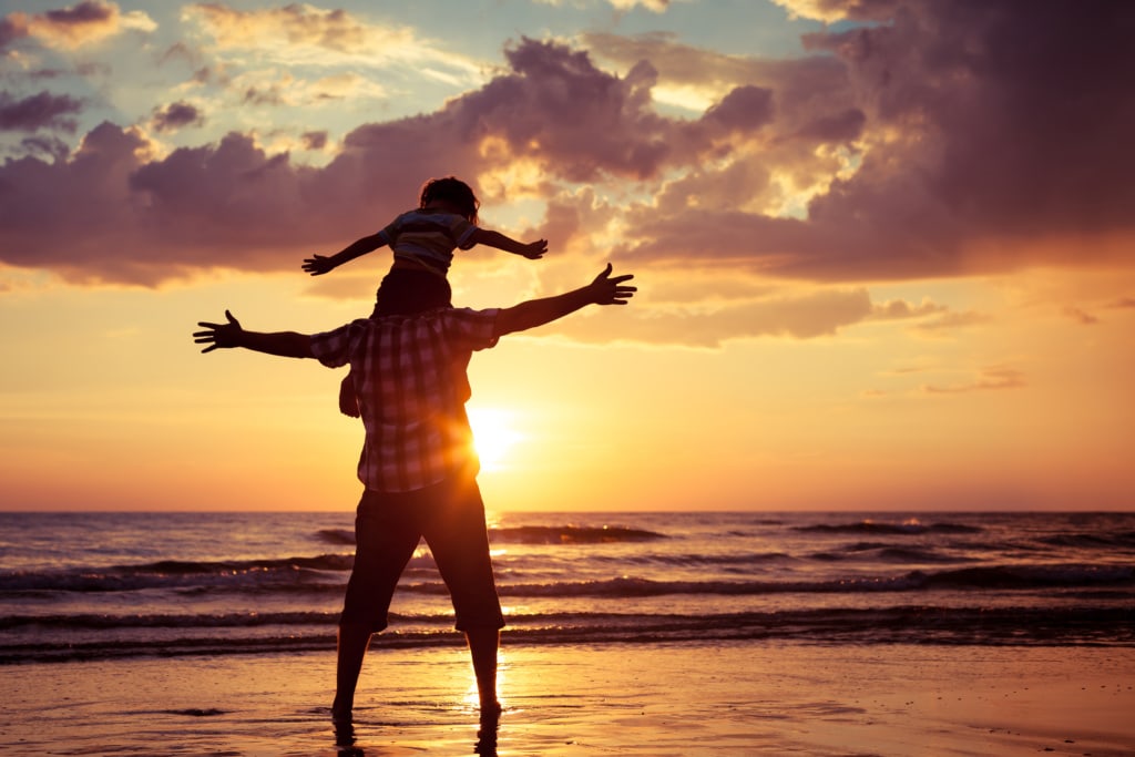 Vater und Sohn am Strand bei Sonnenuntergang