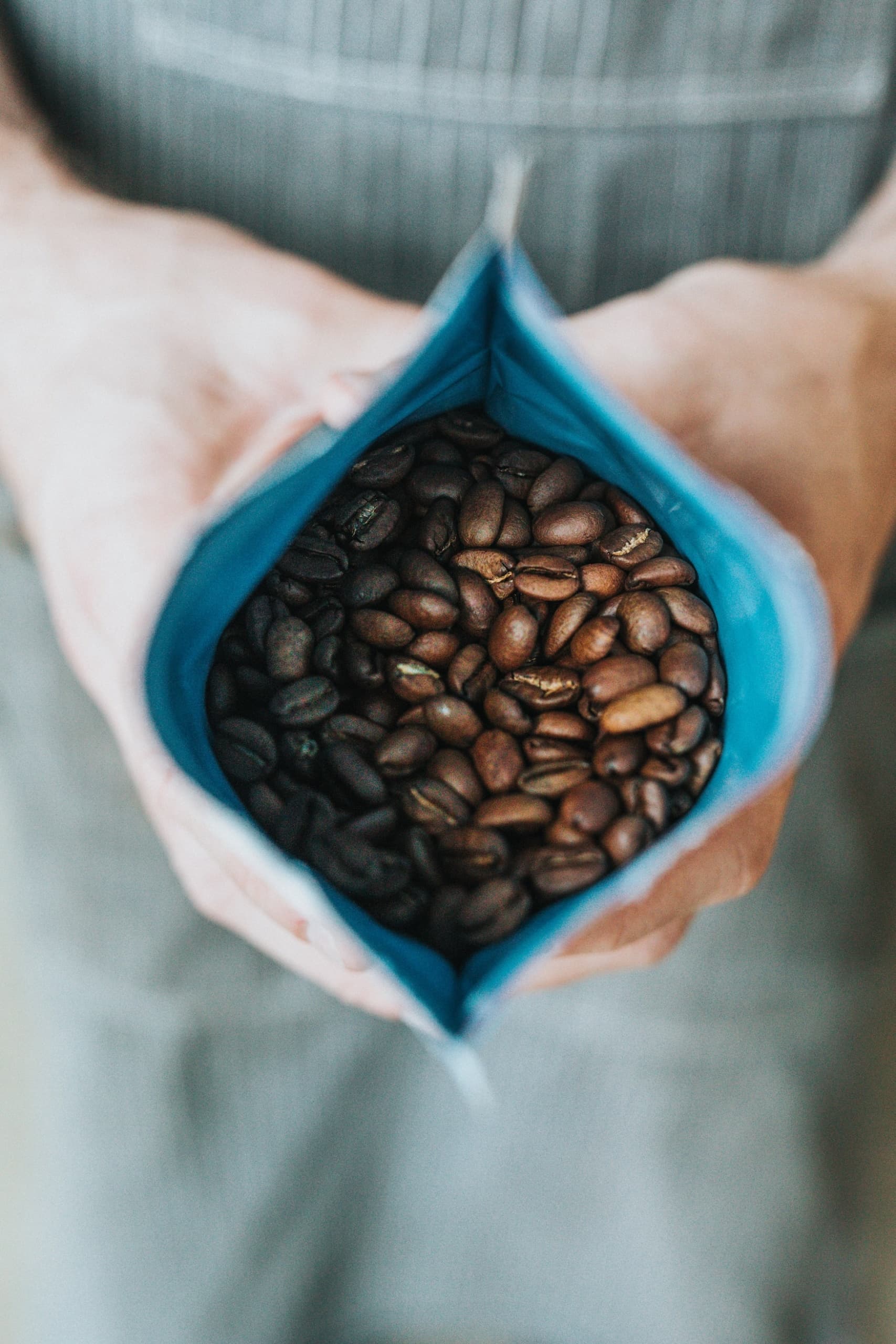 Mann hält Packung mit frisch geröstetem Kaffee in der Hand