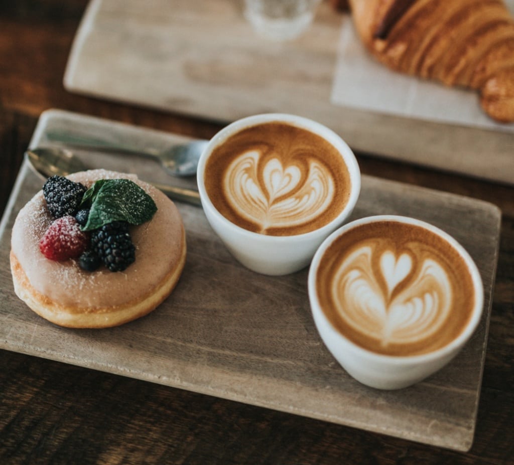 Zwei Kaffeetassen und ein Süßgebäck 