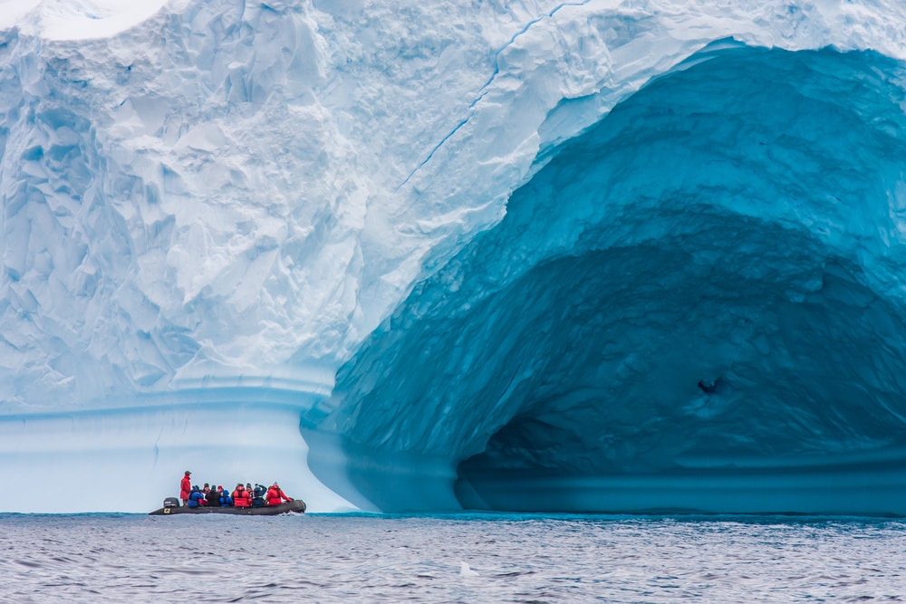 Touristen auf einem Zodiac vor einem Eisberg in der Antarktis