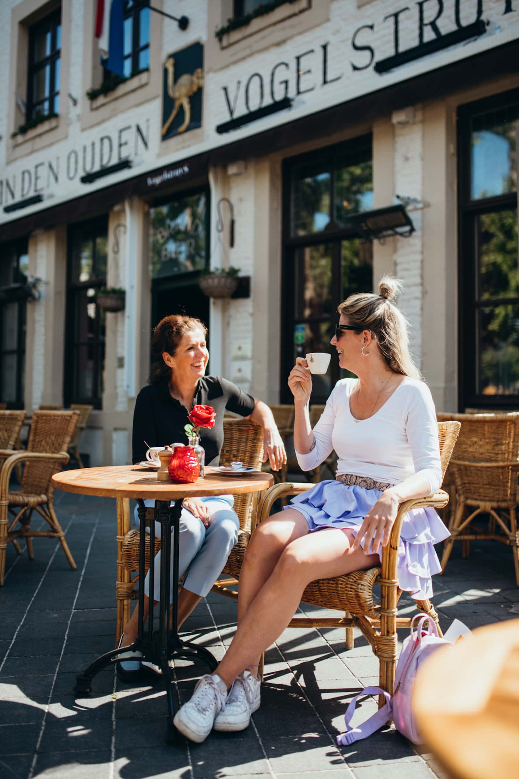 Zwei Frauen sitzen vor Café in Maastricht an einem sonnigen Tag