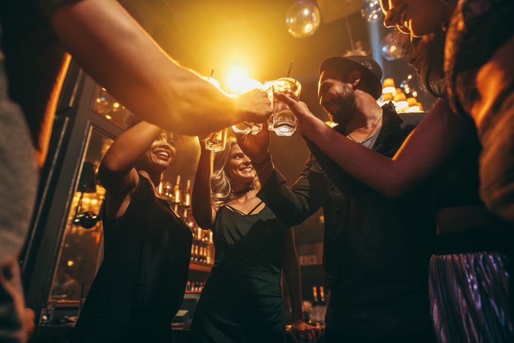 Gruppe von jungen Leuten stößt in Bar an